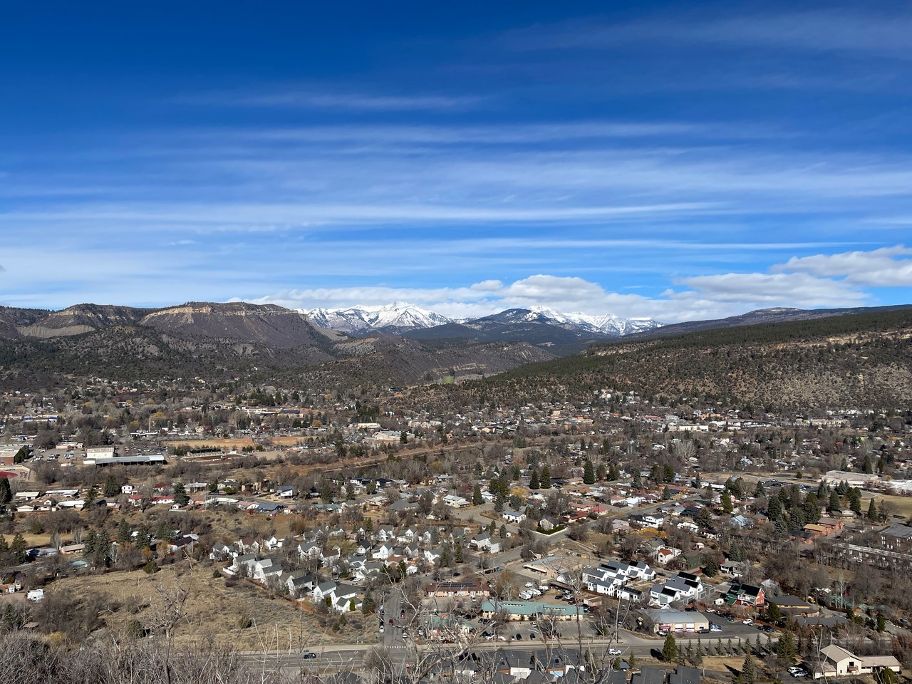 Aerial view of a valley town with snow-covered mountains in the distance.