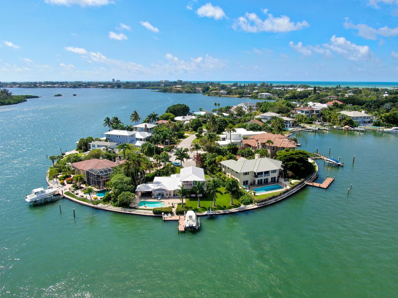 Aerial view of waterfront homes with docks and pools along a tropical peninsula.