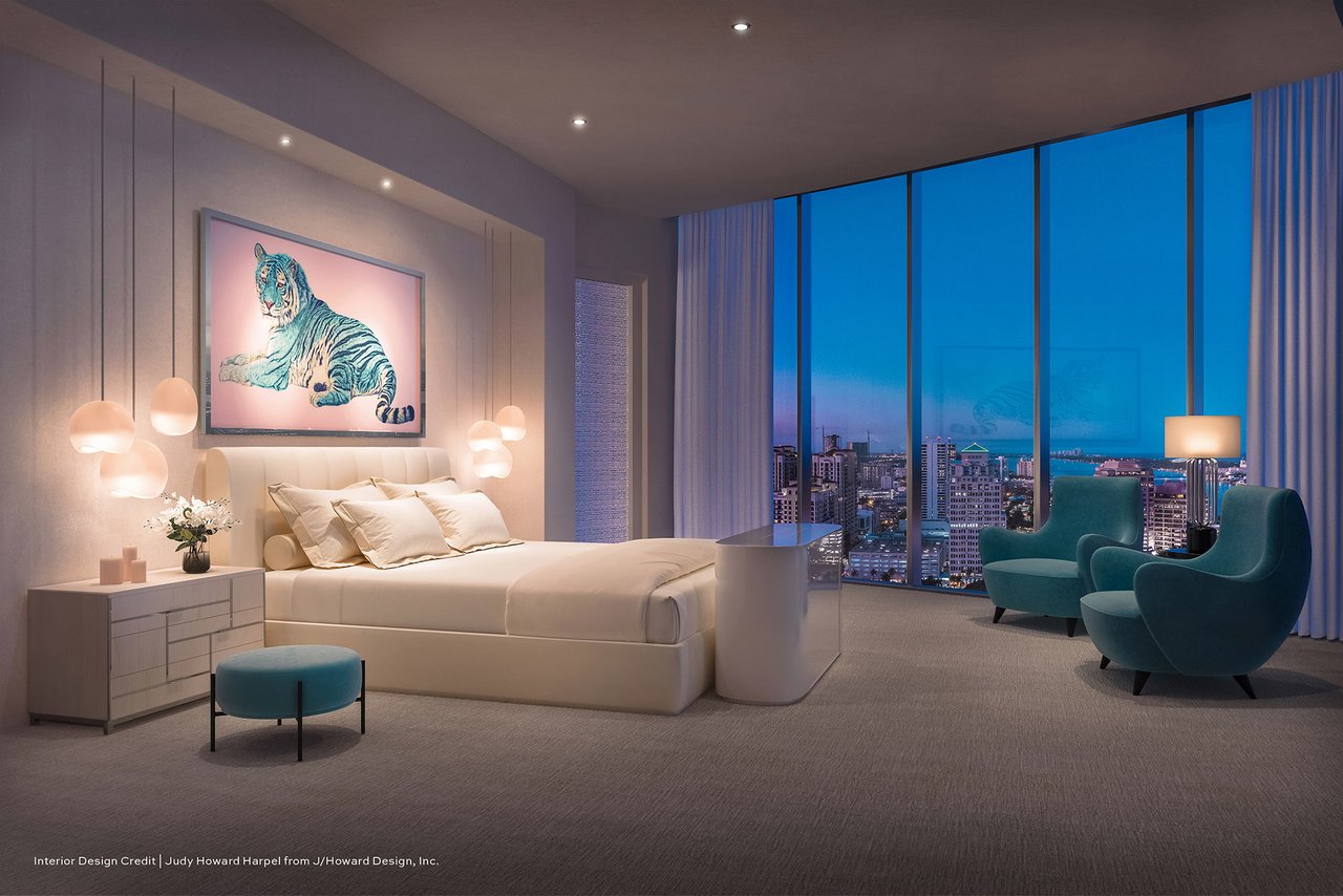 Rendering of the Forté on Flagler penthouse primary bedroom at dusk with a curved window wall and teal lounge chairs.