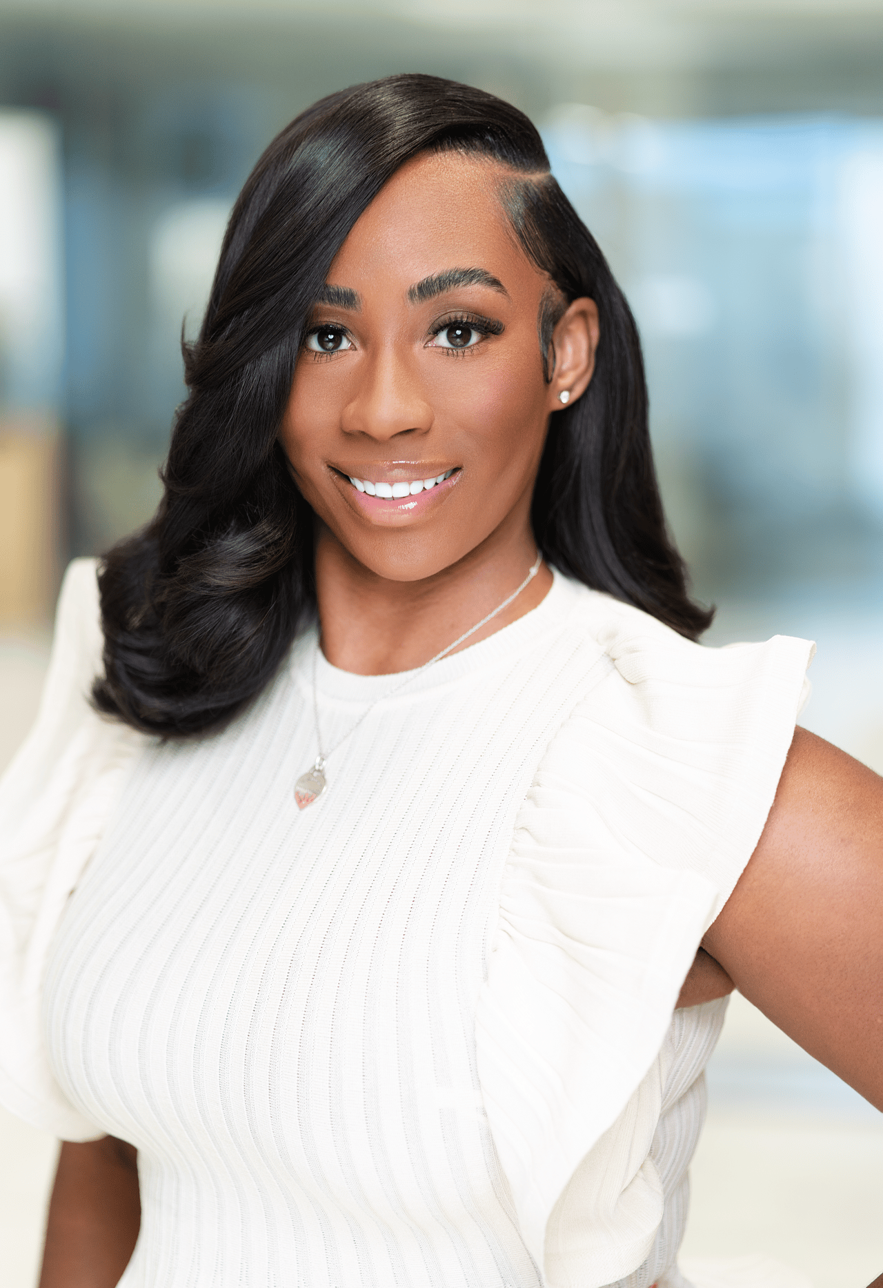 Emone Terrell smiling in a white ruffled-sleeve top, with long dark hair.