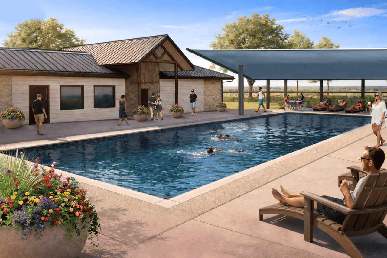 Community pool with swimmers, shaded pavilion, lounge chairs, and a stone-clad building.