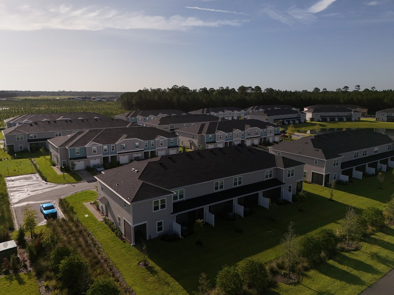 Aerial view of Silver Falls townhomes, with rows of homes, green lawns, and woods beyond.