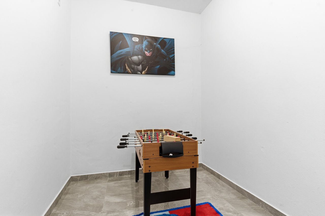 Game room with a wooden foosball table and Batman wall art.