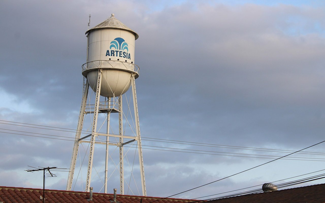 Artesia water tower above rooftops under a cloudy sky