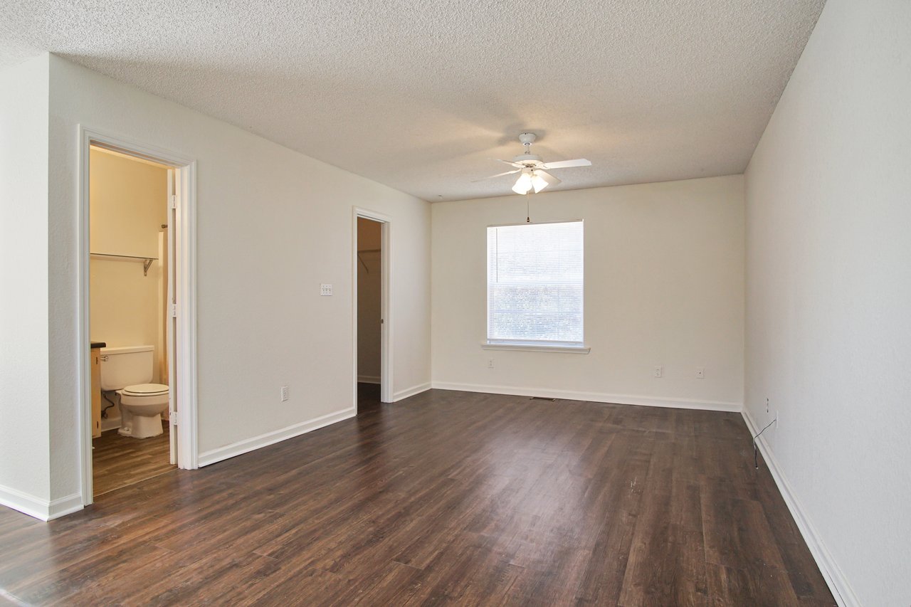 An empty room featuring hardwood floors and pristine white walls, creating a bright and spacious atmosphere.