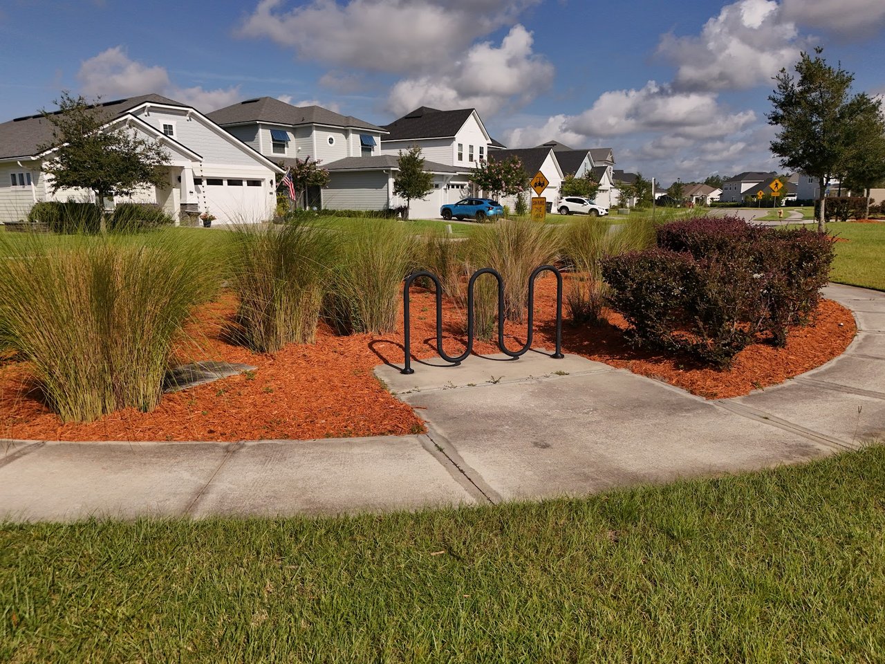 Neighborhood homes along a landscaped street, with a bike rack and Share the Road sign.