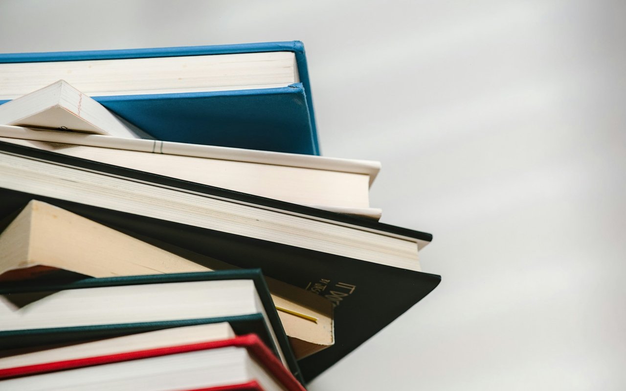 Stack of books with blue, black, green, and red covers.