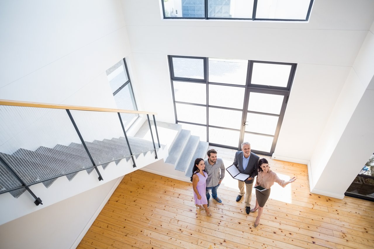 Bright modern home interior with wood floors, a glass-railed staircase, and large windows.
