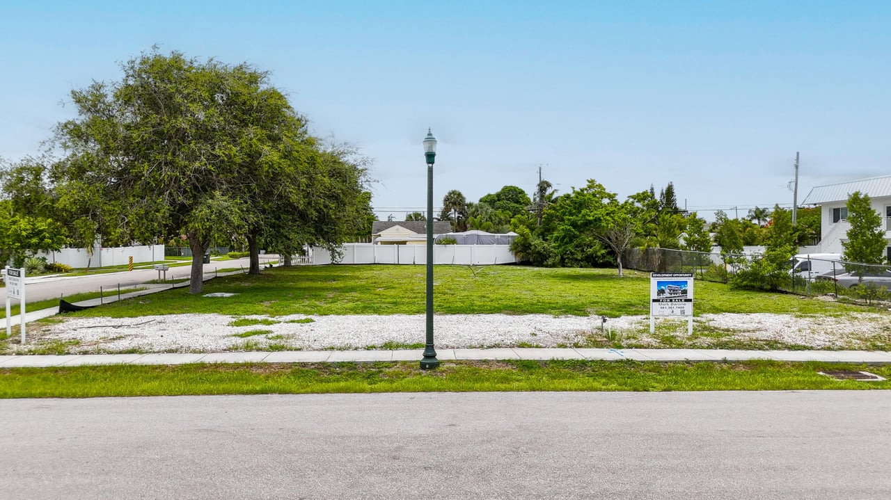 Street-level photo of vacant development lot at 248 SE 1st Ave, Delray Beach, with mature trees and sidewalk frontage.