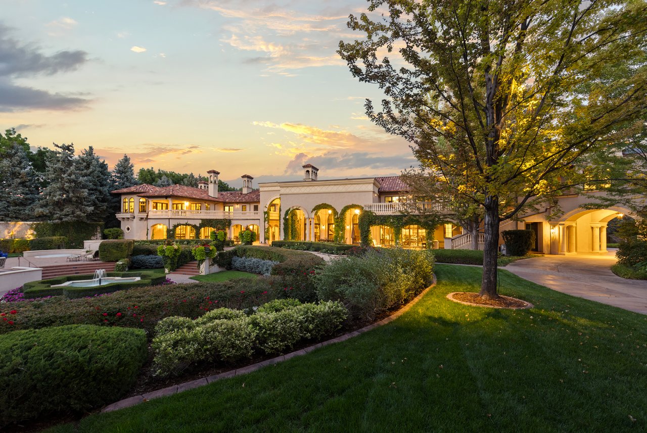 Mediterranean-style estate with formal gardens, a fountain, and mature trees at sunset.