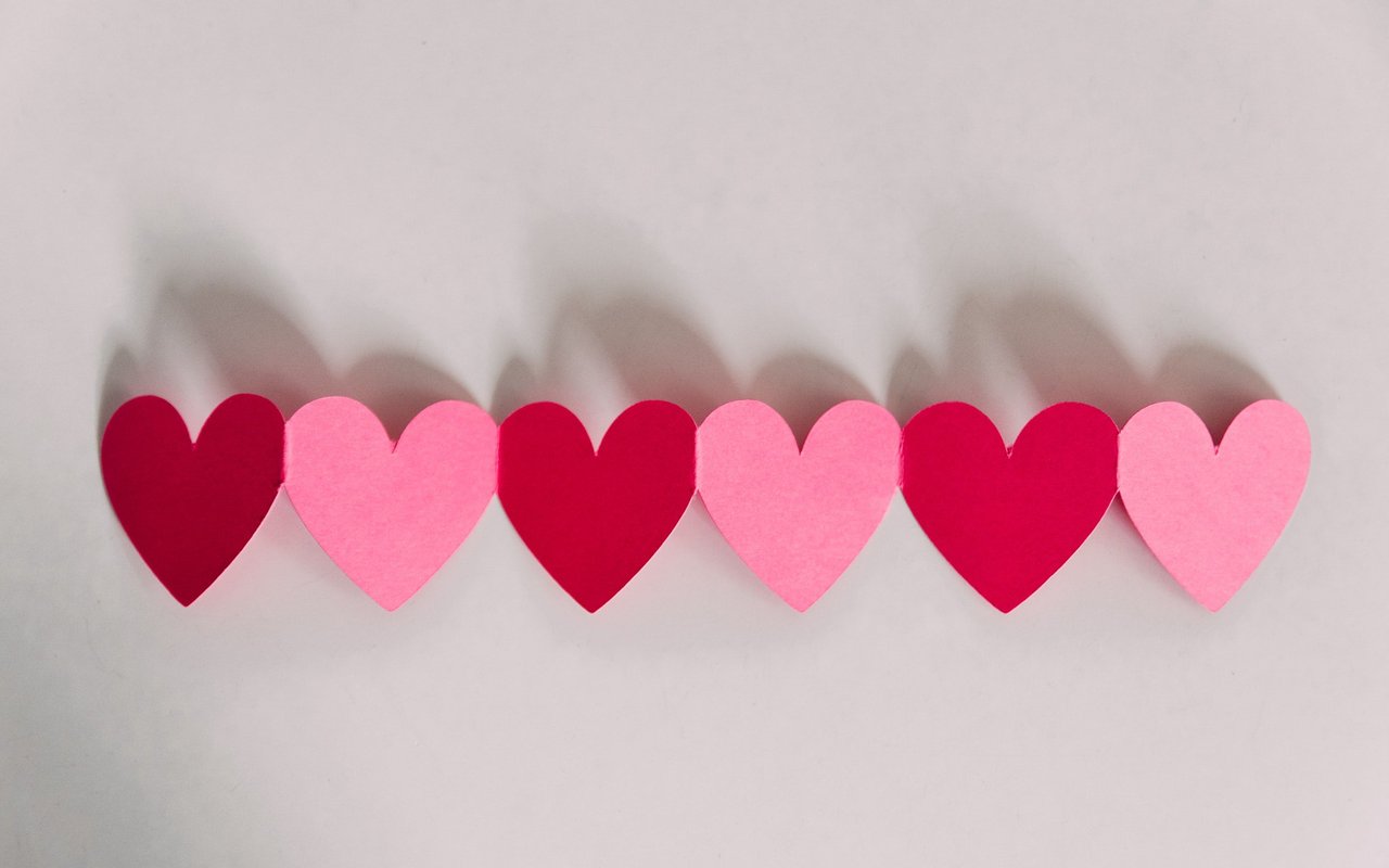 Alternating pink and red paper hearts arranged in a row.