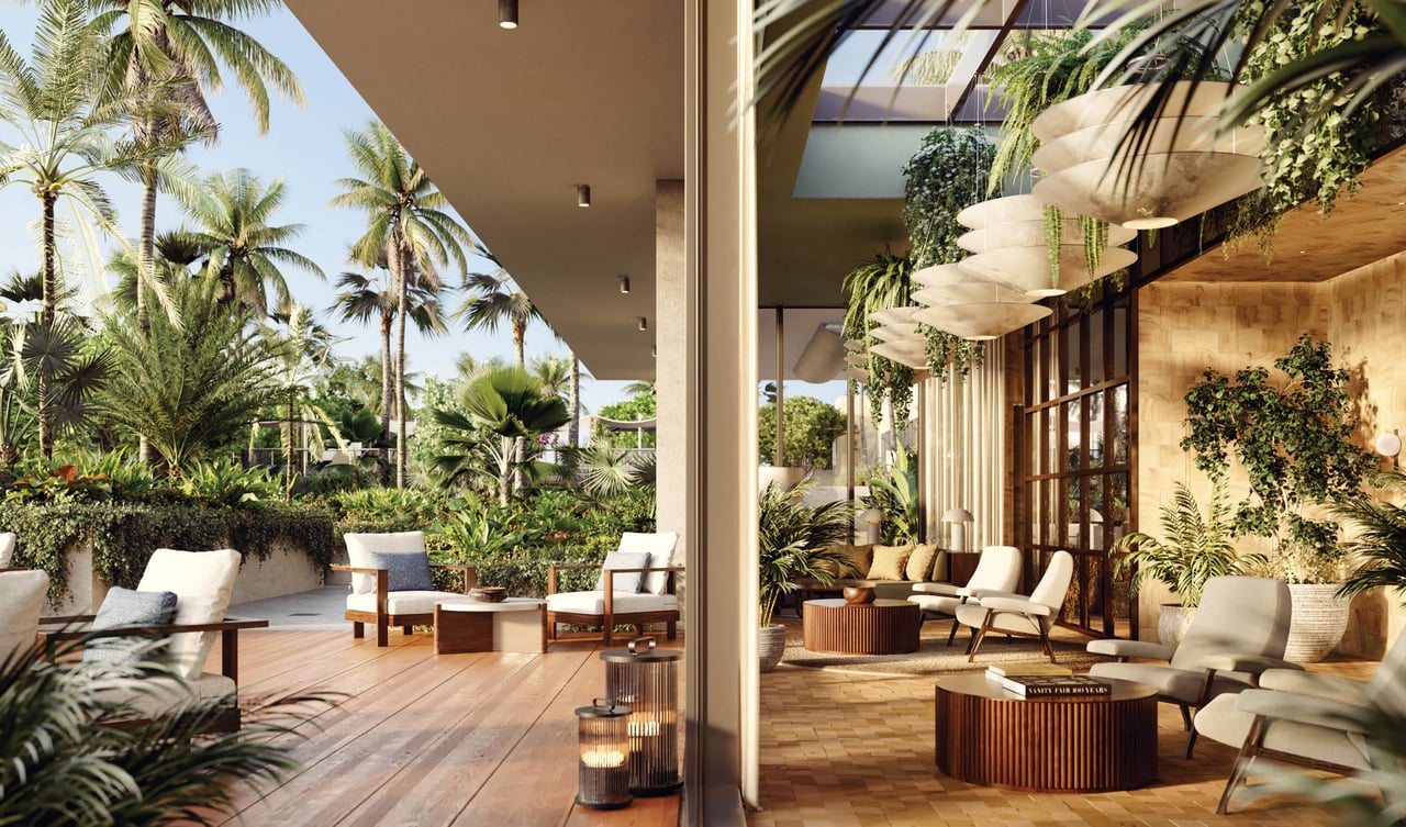 Furnished lounge opening onto a palm-lined terrace, with floor-to-ceiling windows and sculptural pendant lights.