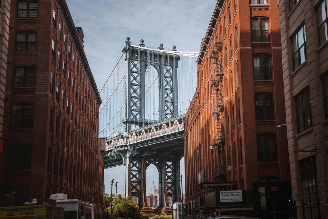A classic view of DUMBO in New York City from Washington Street, featuring the Manhattan Bridge framed between historic buildings.