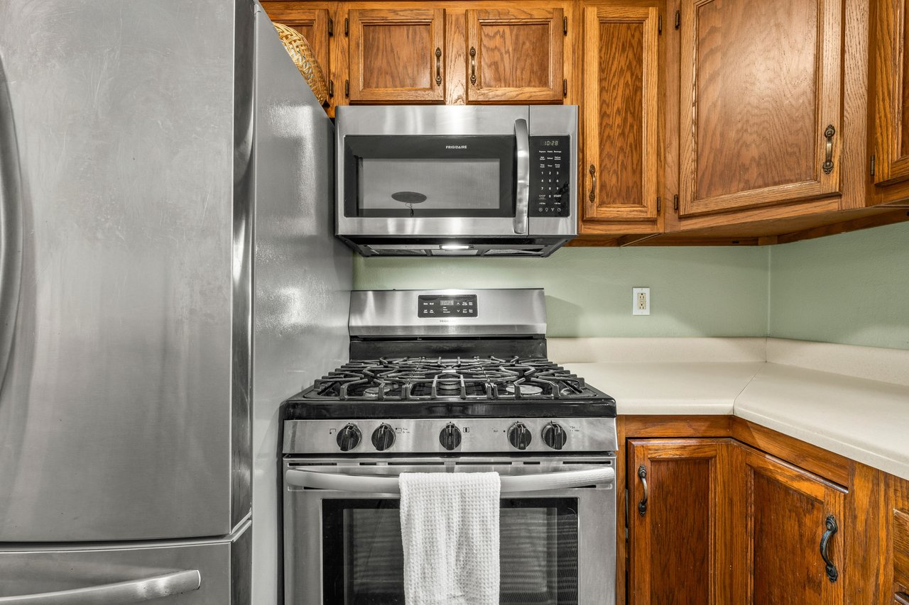 Kitchen with wood cabinets, stainless-steel appliances, and a gas range beneath a microwave.