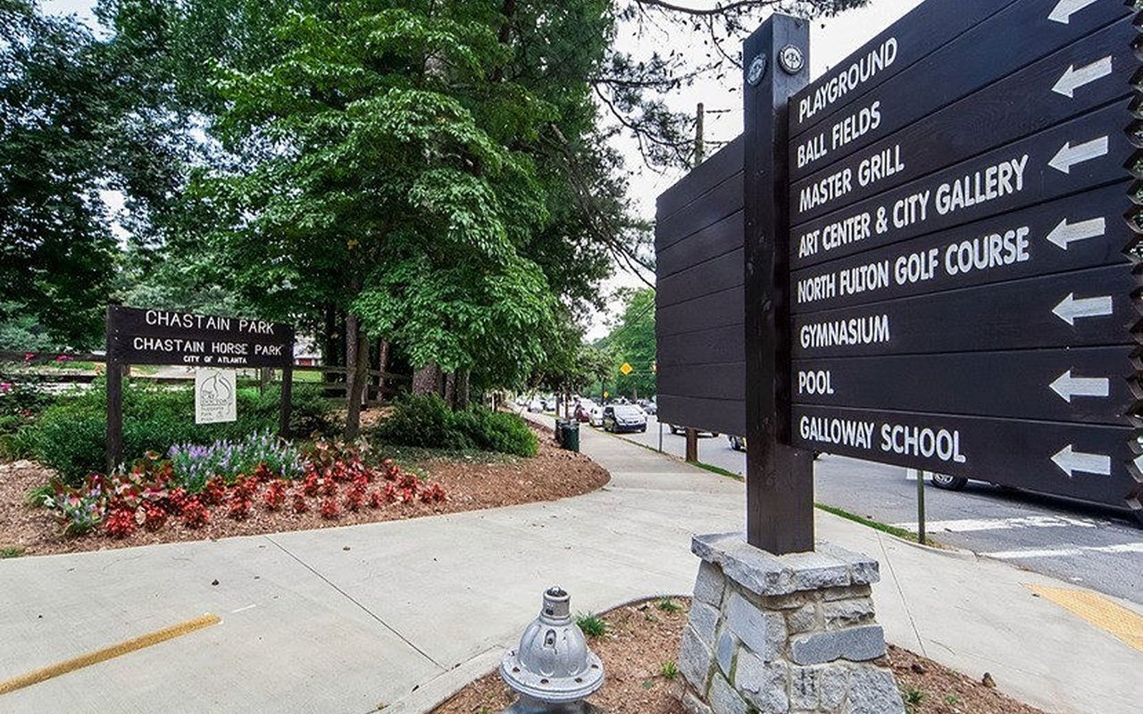 Chastain Park entrance sign beside a directional board listing park amenities.