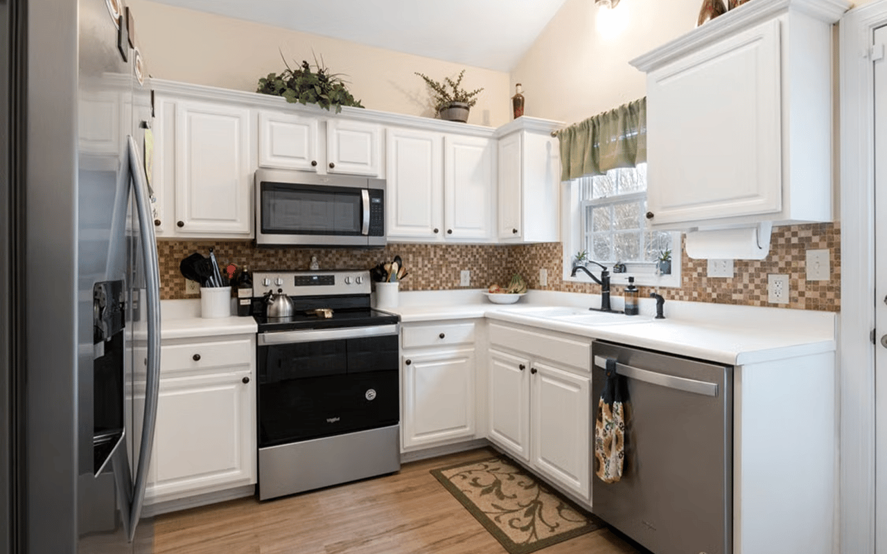 Kitchen with white cabinets, stainless steel appliances, and a mosaic tile backsplash.