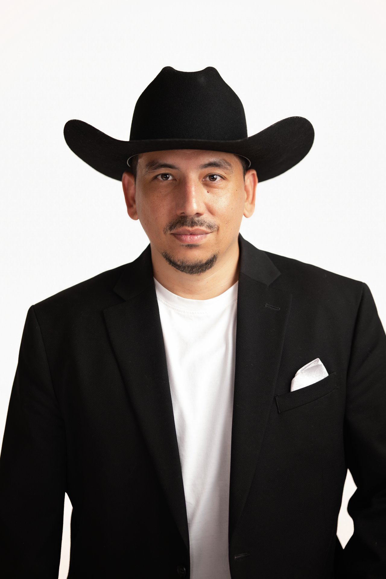 Man in a black cowboy hat and blazer over a white shirt.