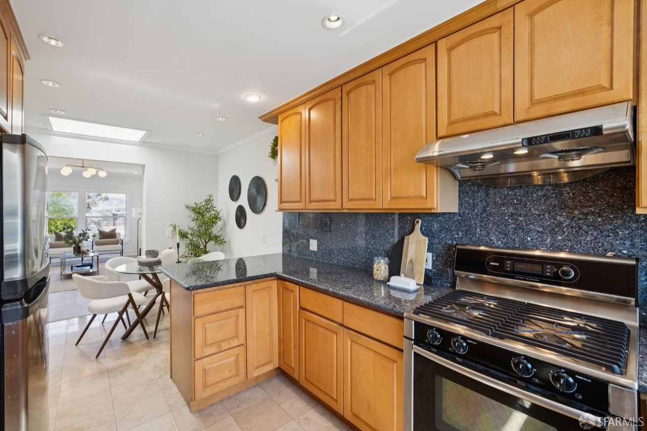 Kitchen with honey-colored cabinets, dark granite counters, and a stainless steel range.