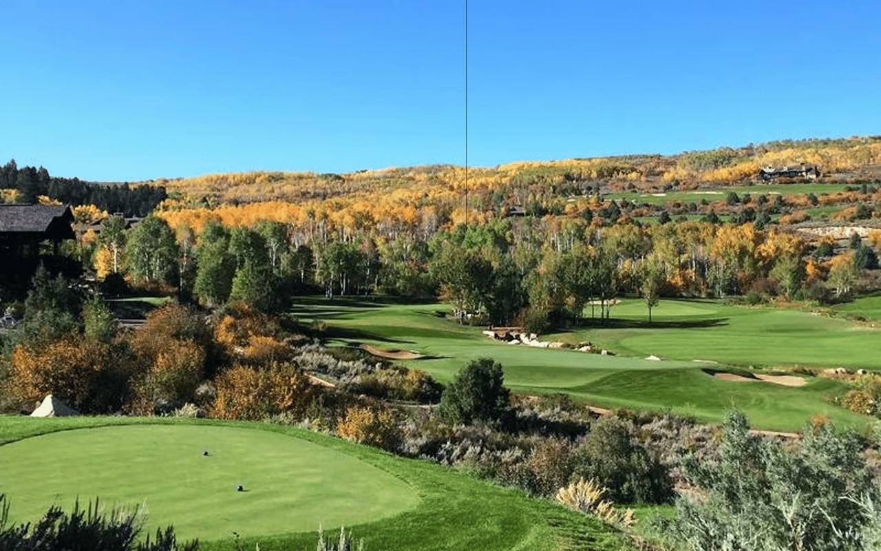 Golf course winding through autumn trees, with sand bunkers and wooded hills in the distance.