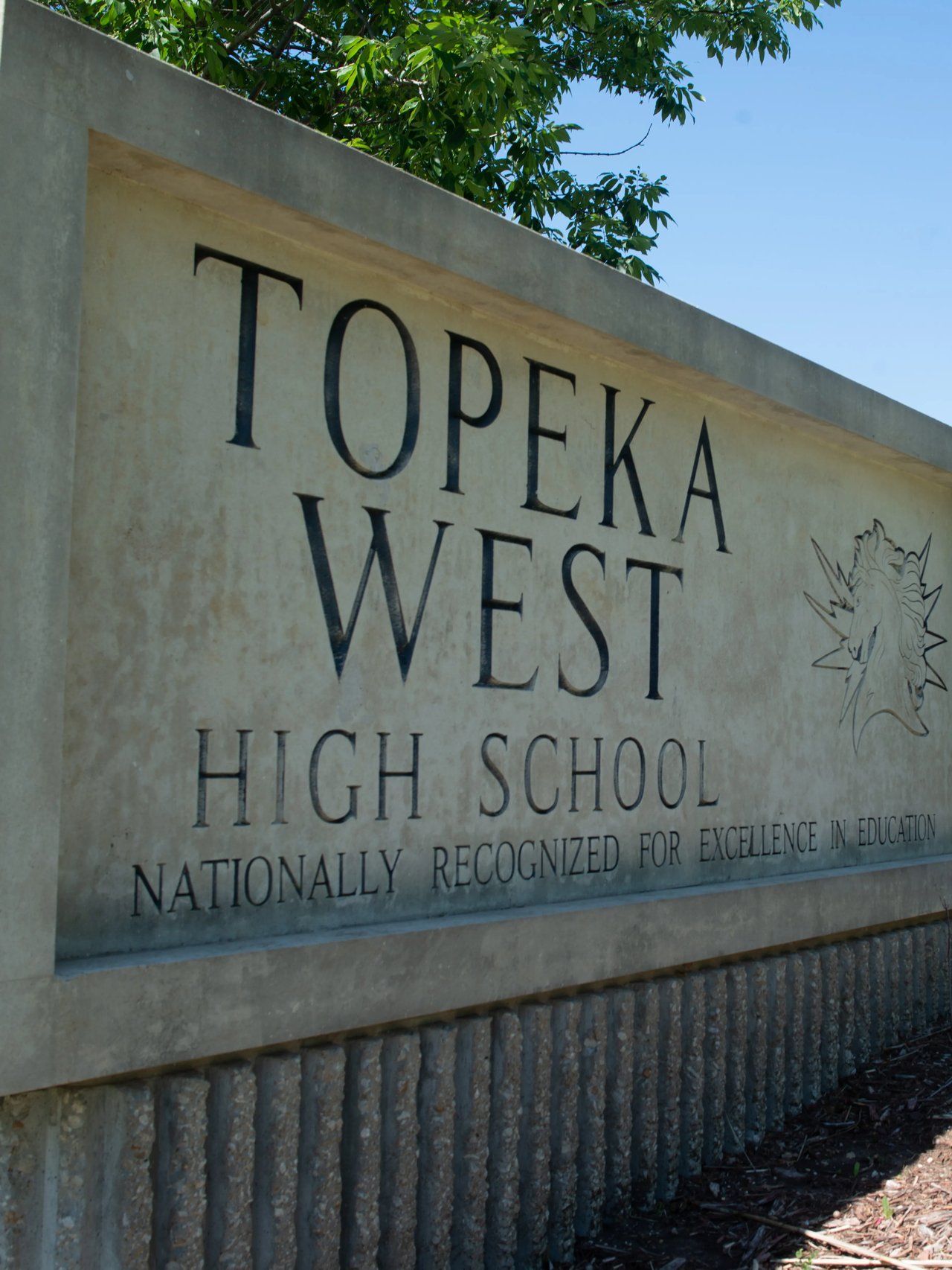 Topeka West High School stone sign with the school’s name and mascot emblem.