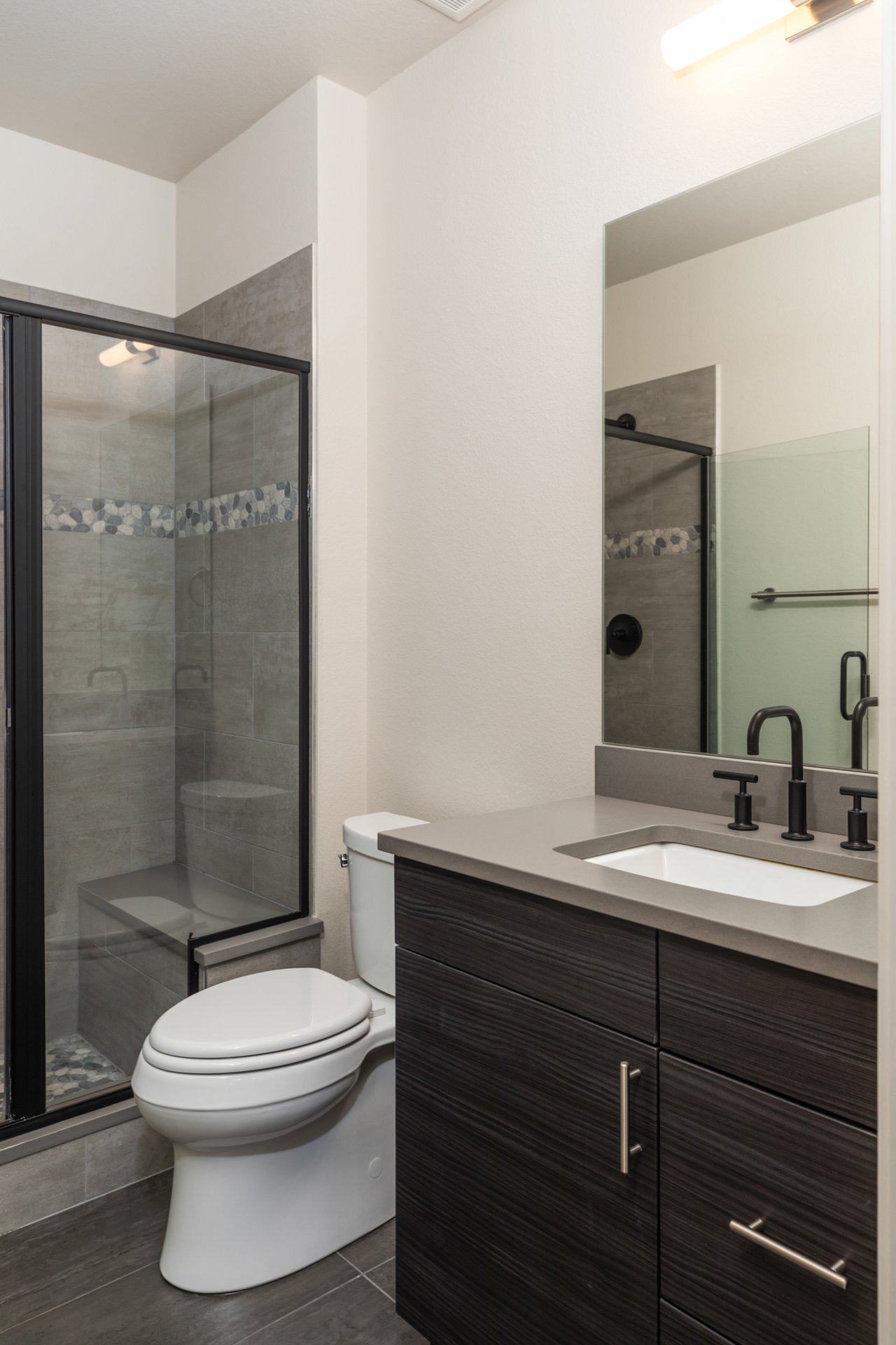 Bathroom with a glass-enclosed tiled shower and matte black fixtures