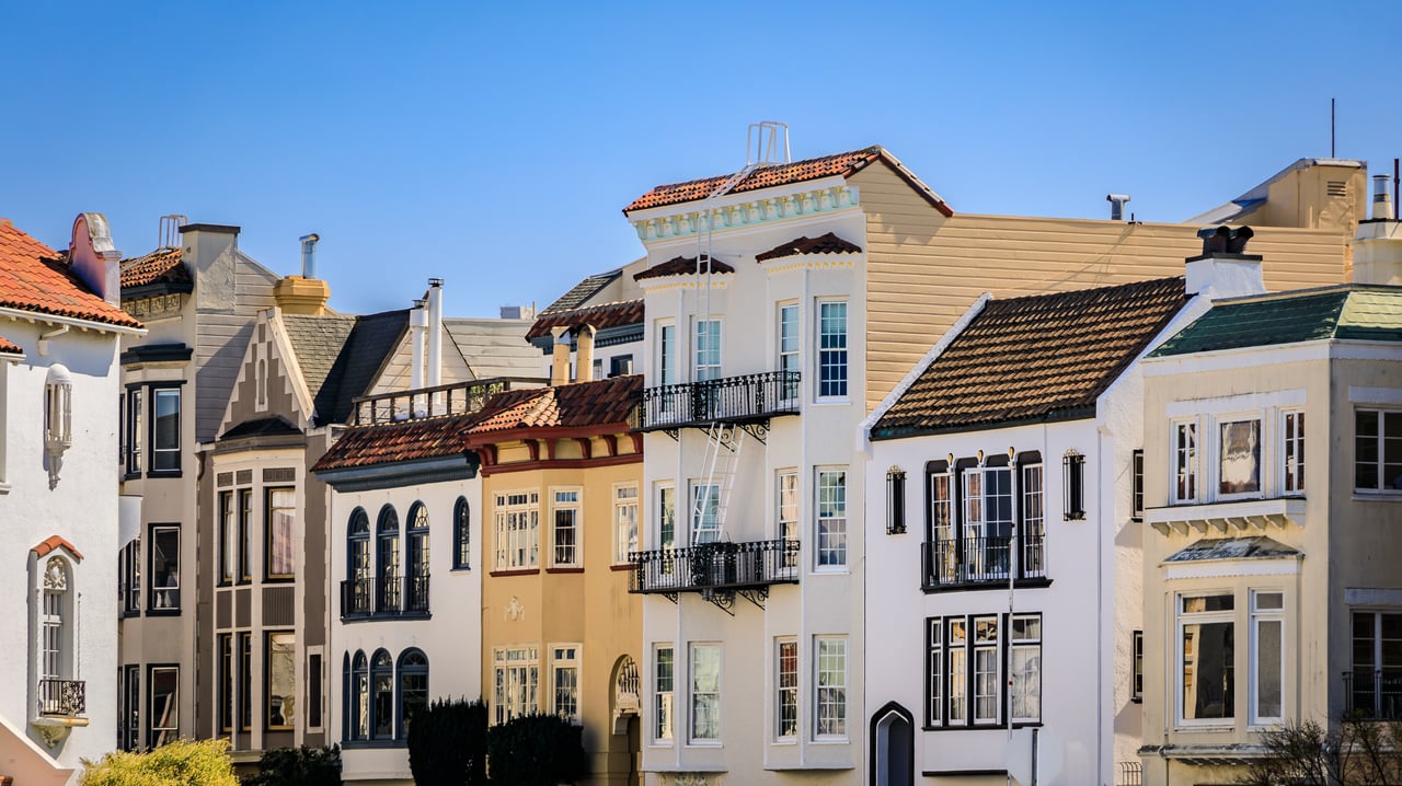 Row of elegant Mediterranean and Spanish-style homes in San Francisco’s Marina District, featuring ornate façades, arched windows, and tiled roofs under a clear blue sky.
