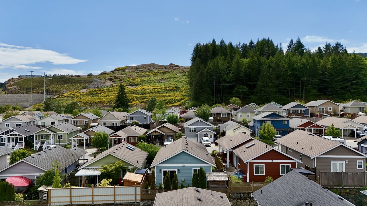 A scenic view of charming single-family homes along 2919 Burlington Crescent in Victoria, BC, nestled against a backdrop of greenery and hills.