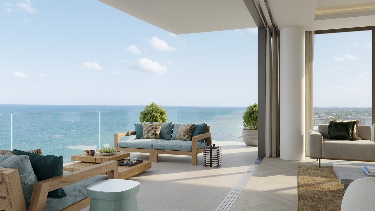Furnished oceanfront terrace with glass railing, blue seating, and views across the water.