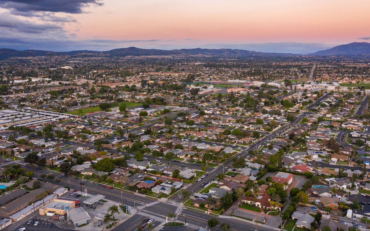 Aerial panorama of Brea neighborhoods and distant hills beneath a pink dusk sky.