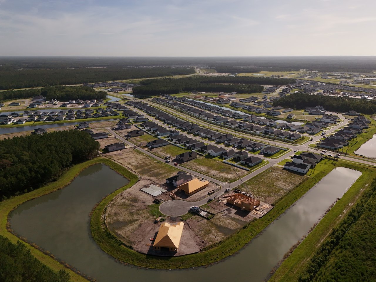 Aerial view of a residential development with homes under construction beside winding water channels.