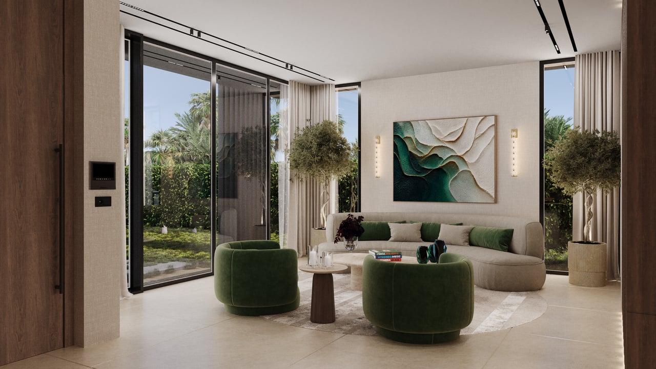 Staged living room with green lounge chairs, a curved beige sofa, and glass doors overlooking a garden.