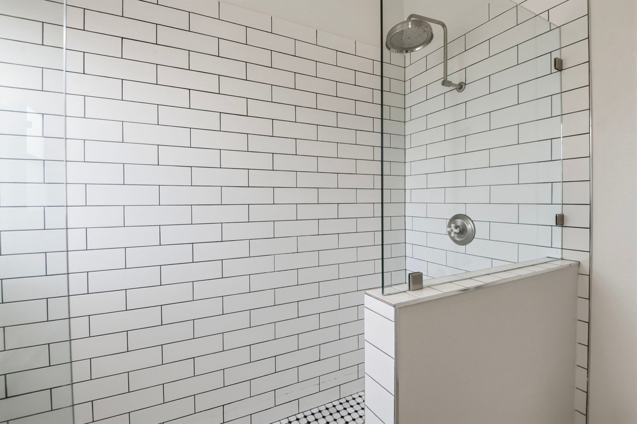 Walk-in shower with white subway tile surround, glass enclosure, and brushed nickel fixtures