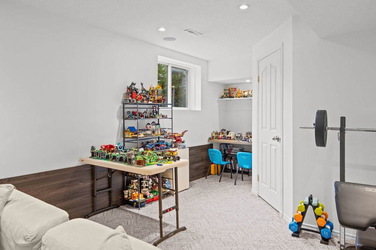 Basement recreation room with colorful building-block displays, a white sofa, and workout equipment.