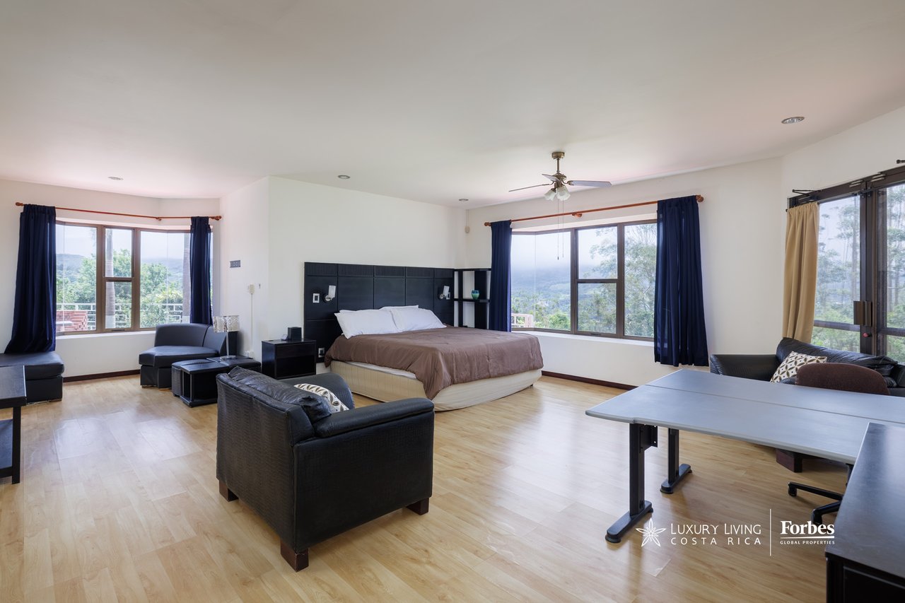 Furnished bedroom with a king-size bed and mountain views through large windows.