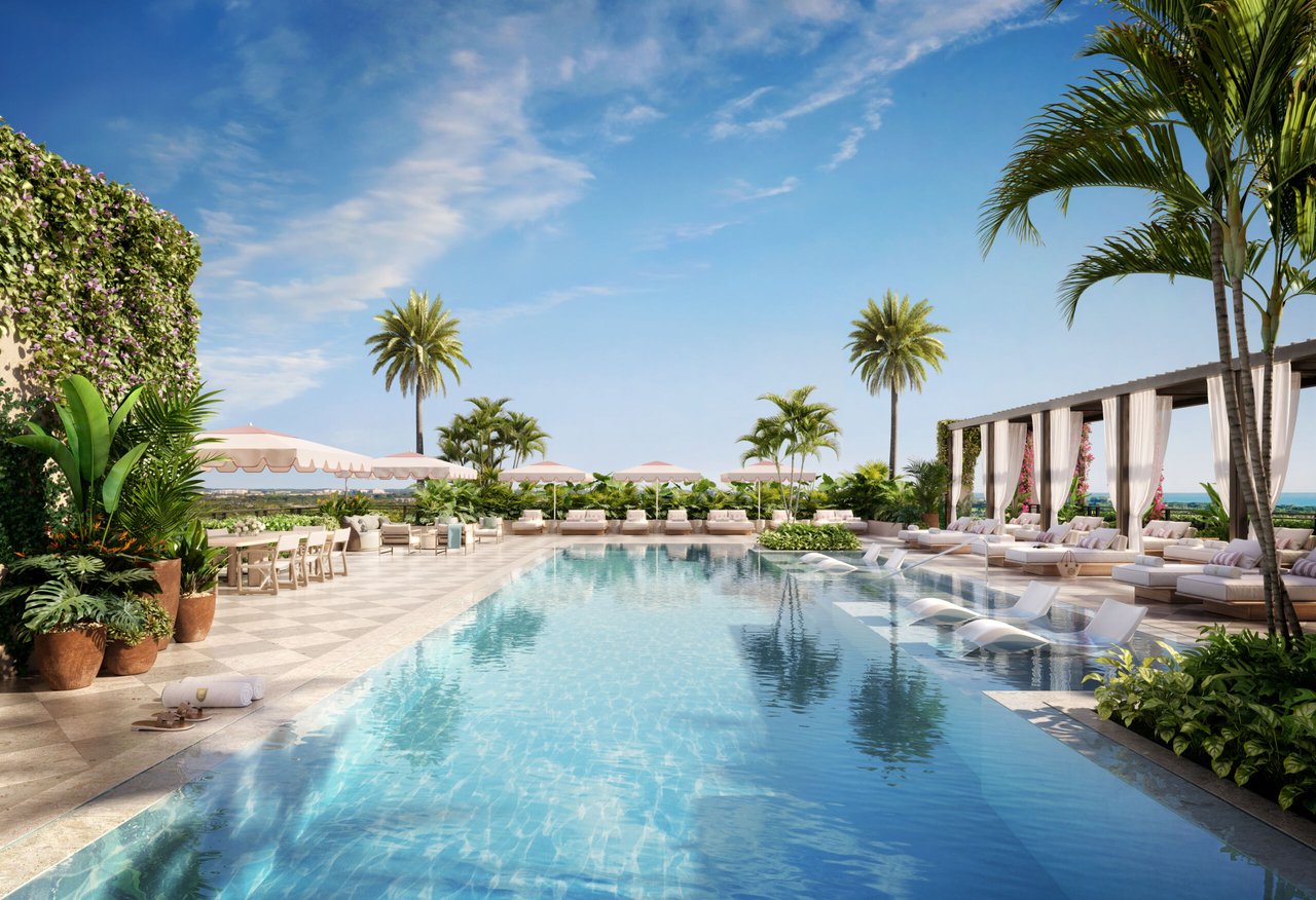 Condominium pool terrace with in-pool loungers, palm trees, and curtained cabanas.