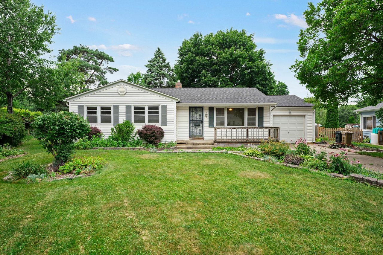 Front exterior of 9 Fremont Circle, a single-story ranch in the Brentwood Village neighborhood of Madison, WI, with a covered front porch, attached garage, and perennial garden beds.