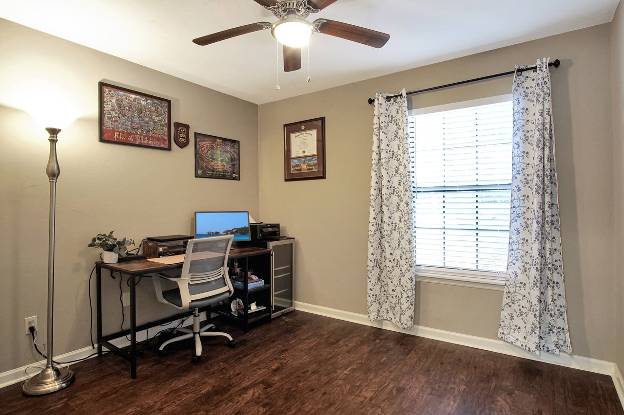 A well-organized home office featuring a desk, chair, and a ceiling fan for comfort and productivity.