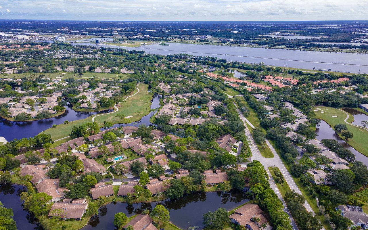 Aerial view of homes, golf fairways and ponds in a tree-lined community.