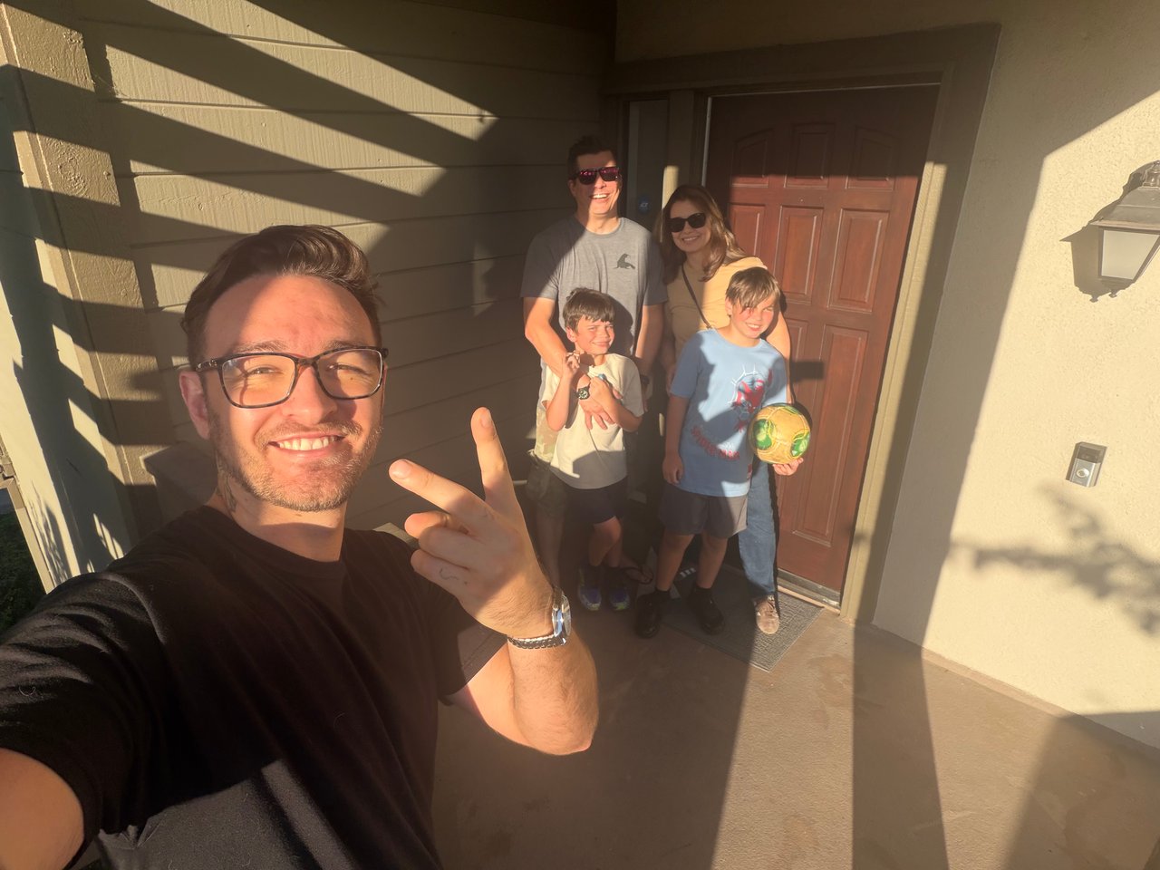 Real estate agent takes a sunny porch selfie with two parents and their children.
