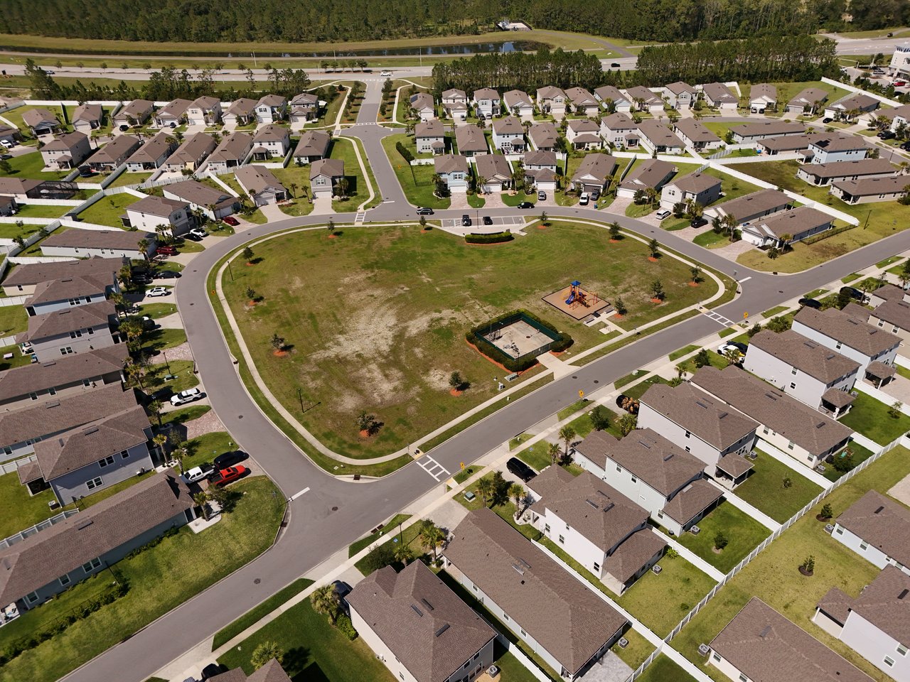 Aerial view of homes around a grassy neighborhood common with a playground.