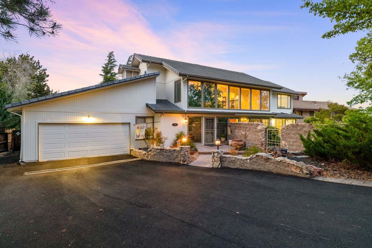 Mid-century modern home exterior in Reno at twilight with large windows, two-car garage, and landscaped front entry