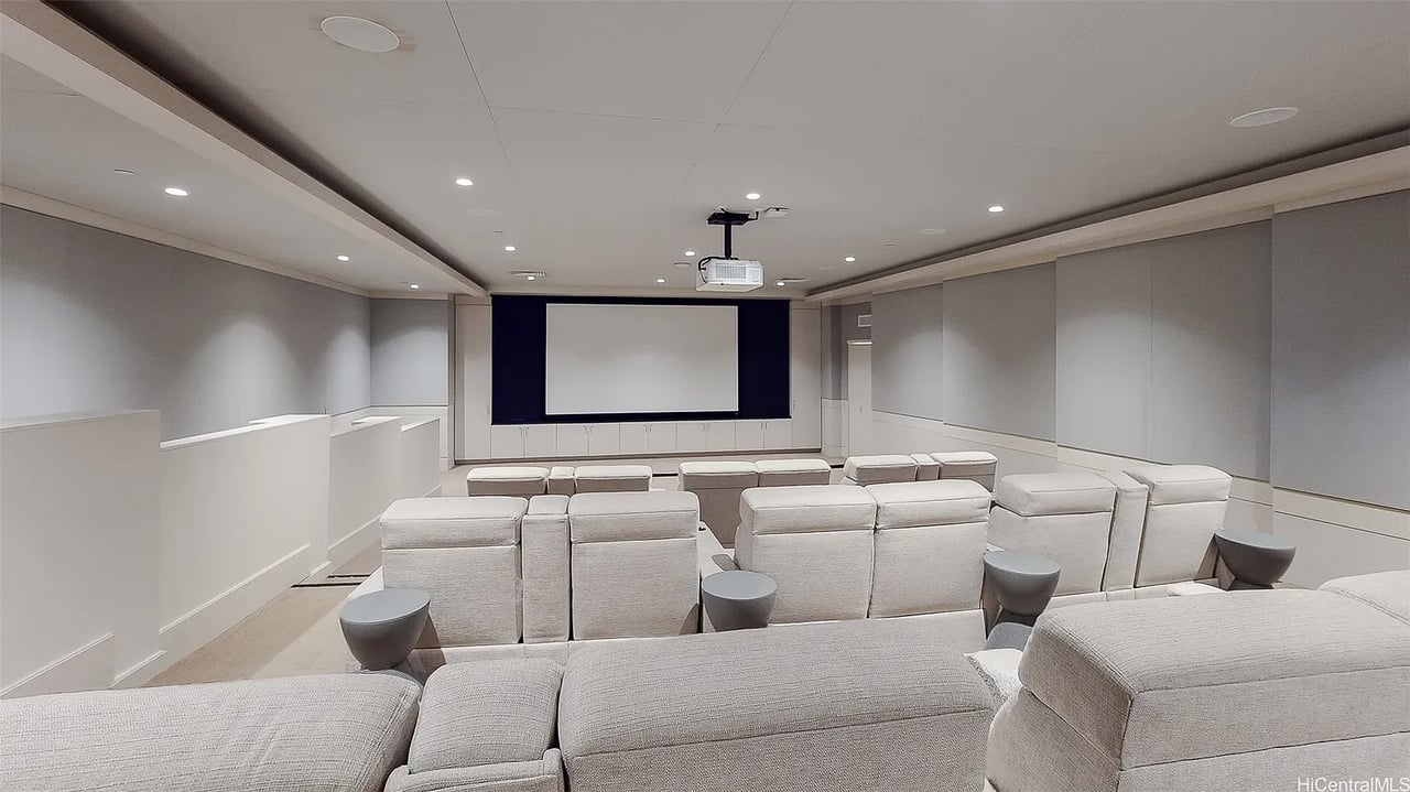 Screening room with rows of pale seats facing a large projection screen.