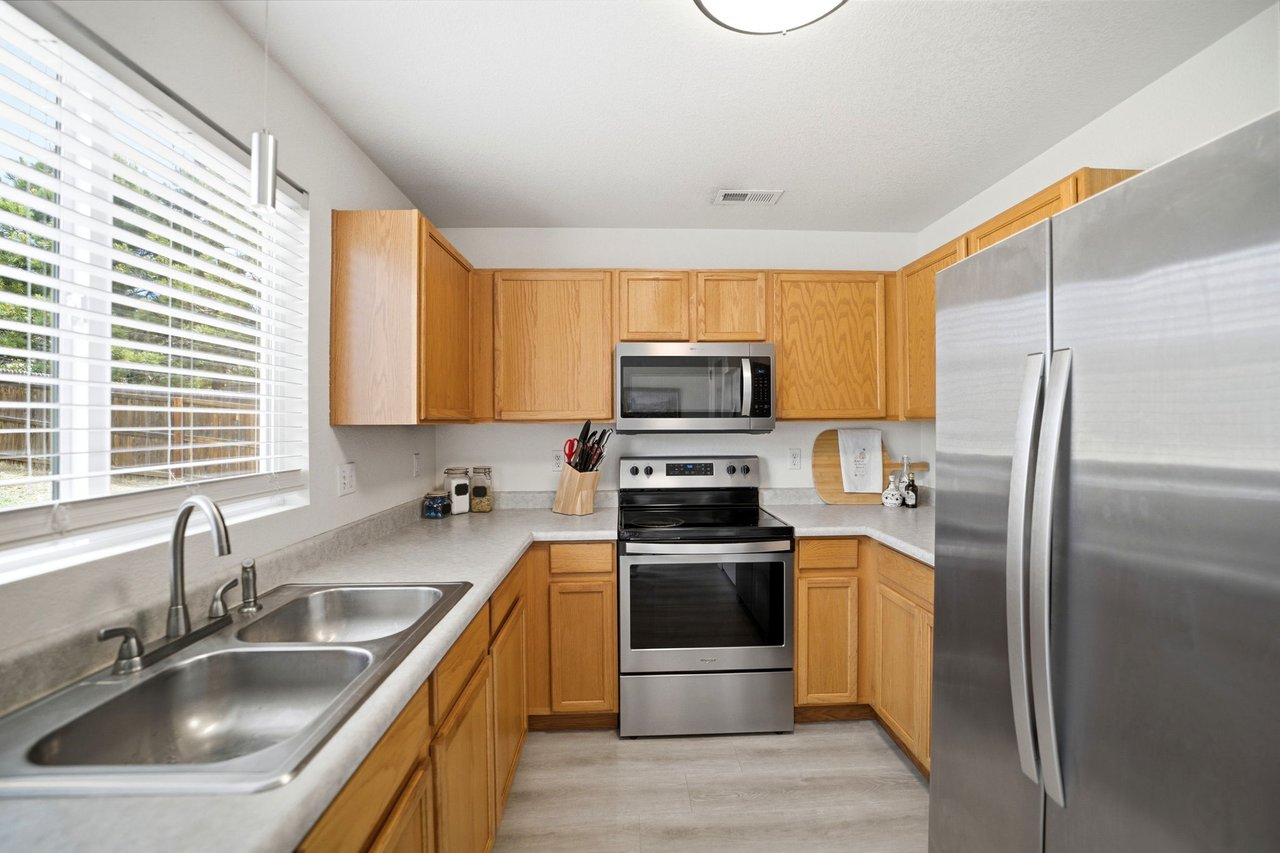 Kitchen with double sink, window, and stainless steel refrigerator