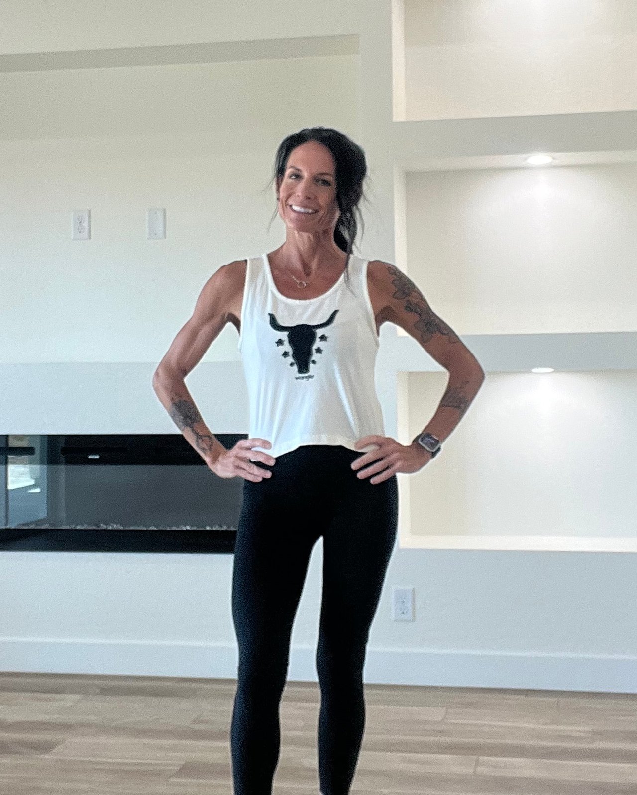 Woman standing with hands on hips in a bright, modern home interior.