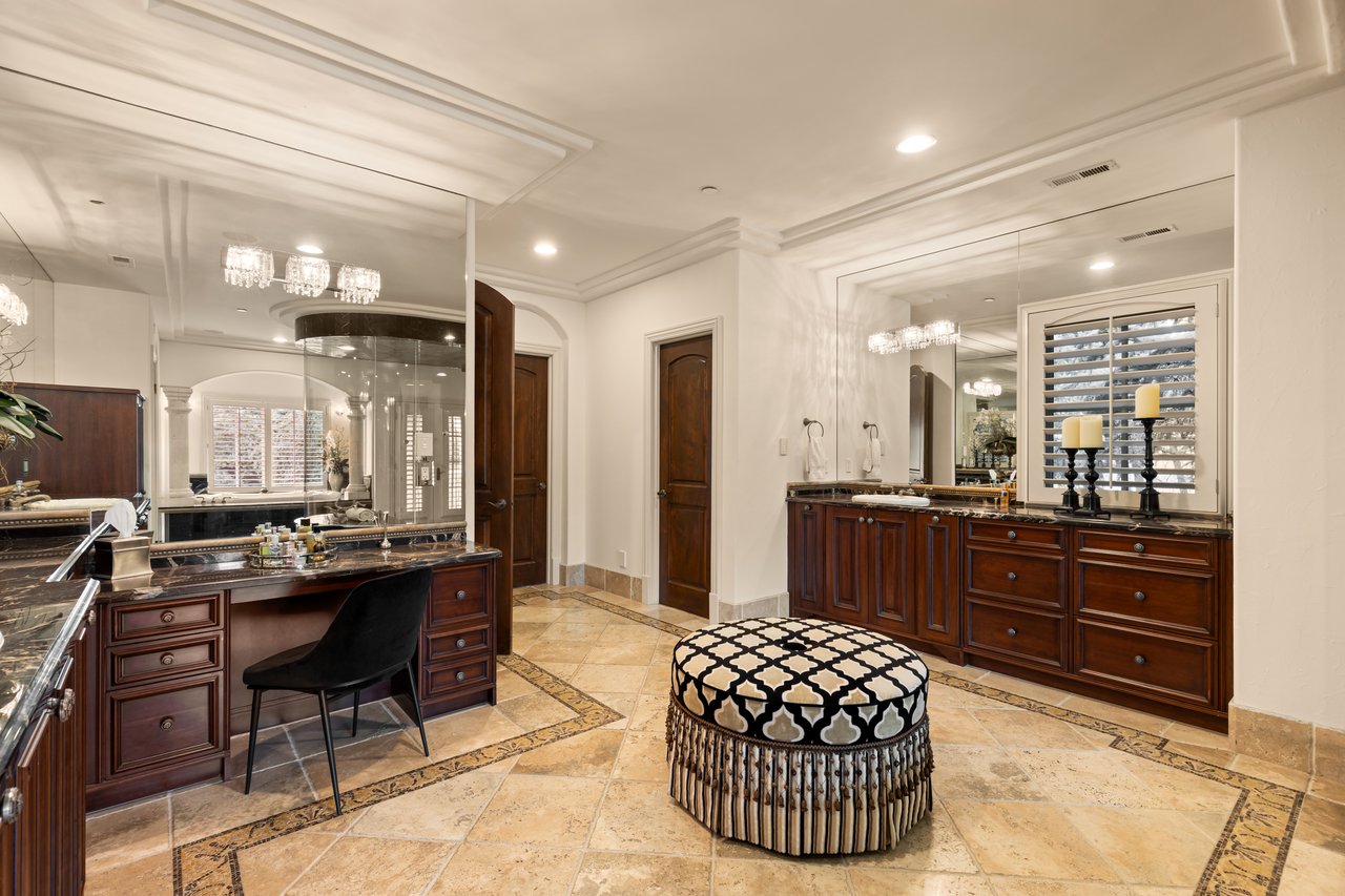 Bathroom with dark wood vanities, mirrored walls, tiled floor, and a patterned round stool.