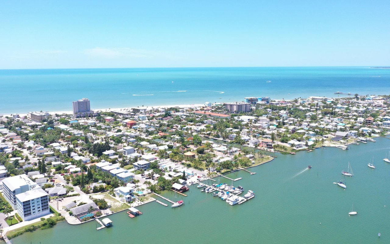 Coastal neighborhood with waterfront homes and boats in a marina beside the blue sea.