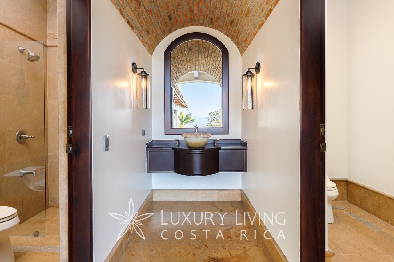 Bathroom with a dark wood vanity and stone vessel sink beneath an arched brick ceiling.