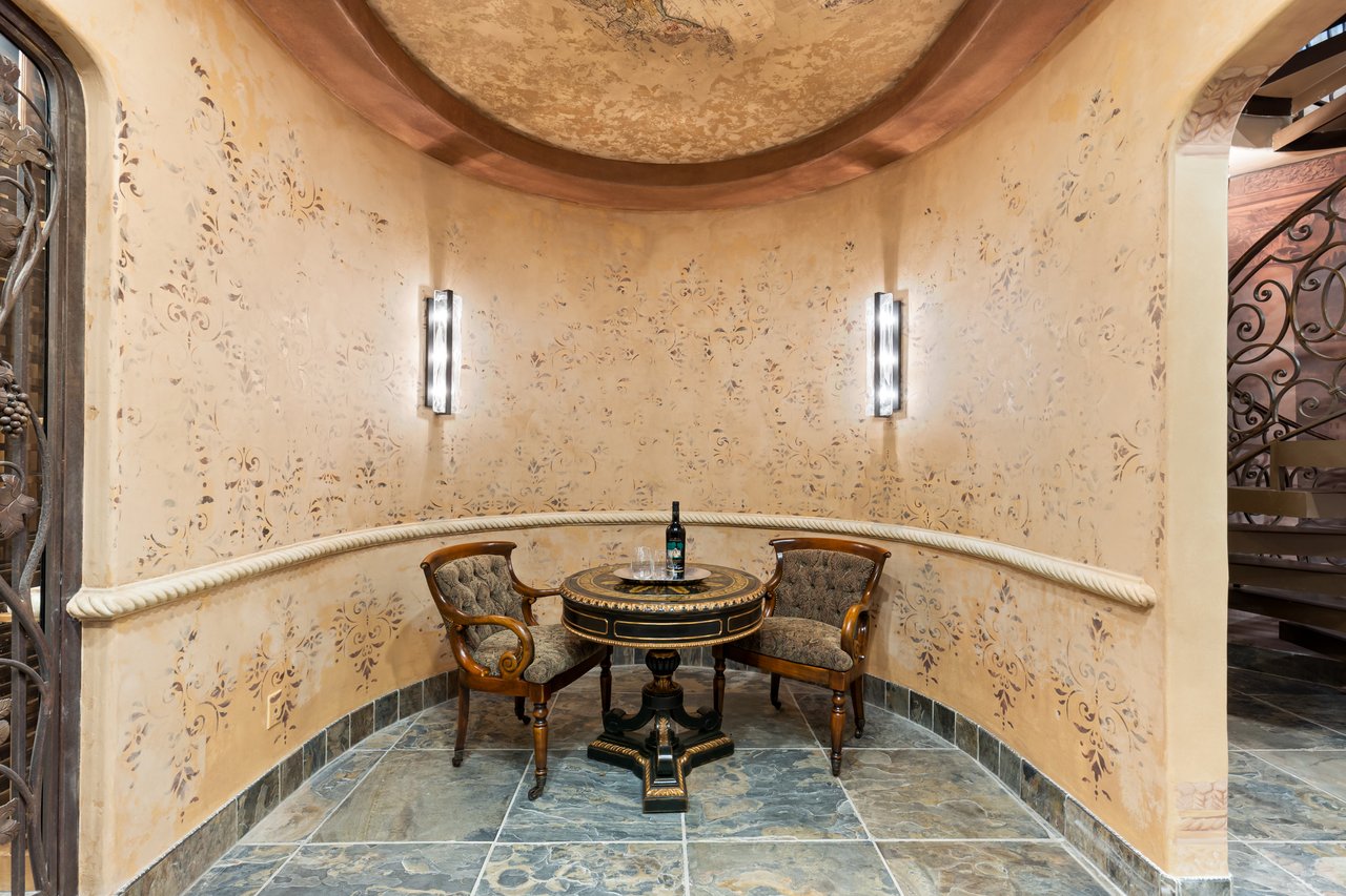 Furnished sitting alcove with patterned plaster walls, two chairs, and a round decorative table.
