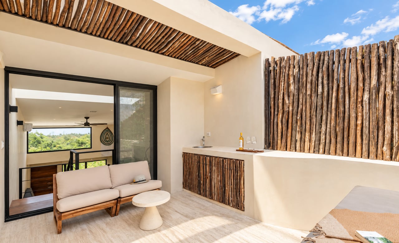 Furnished terrace with a pale sofa, outdoor bar and sink, and rustic wood screens.