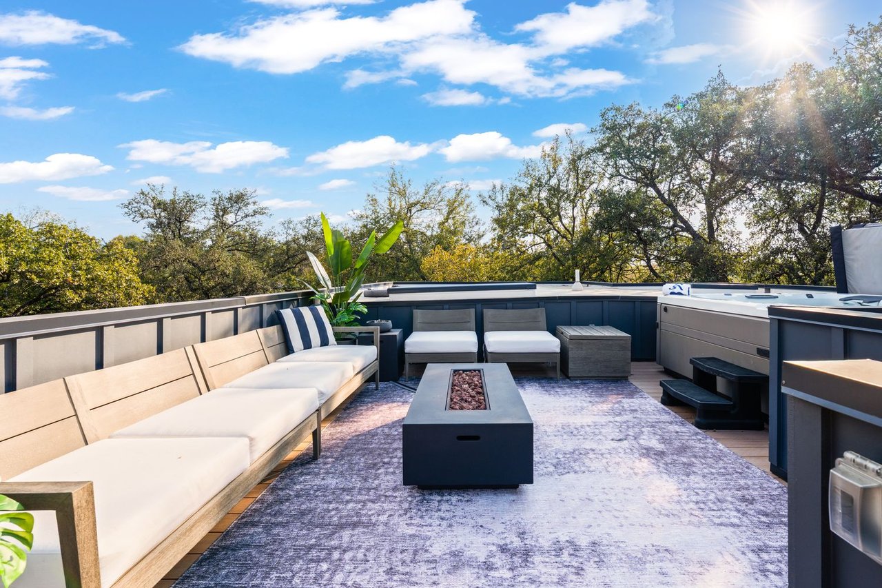 Rooftop terrace with cushioned seating, a fire table, and a built-in hot tub.